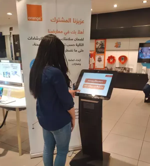 woman using SEDCO's queuing kiosk at Orange Jordan